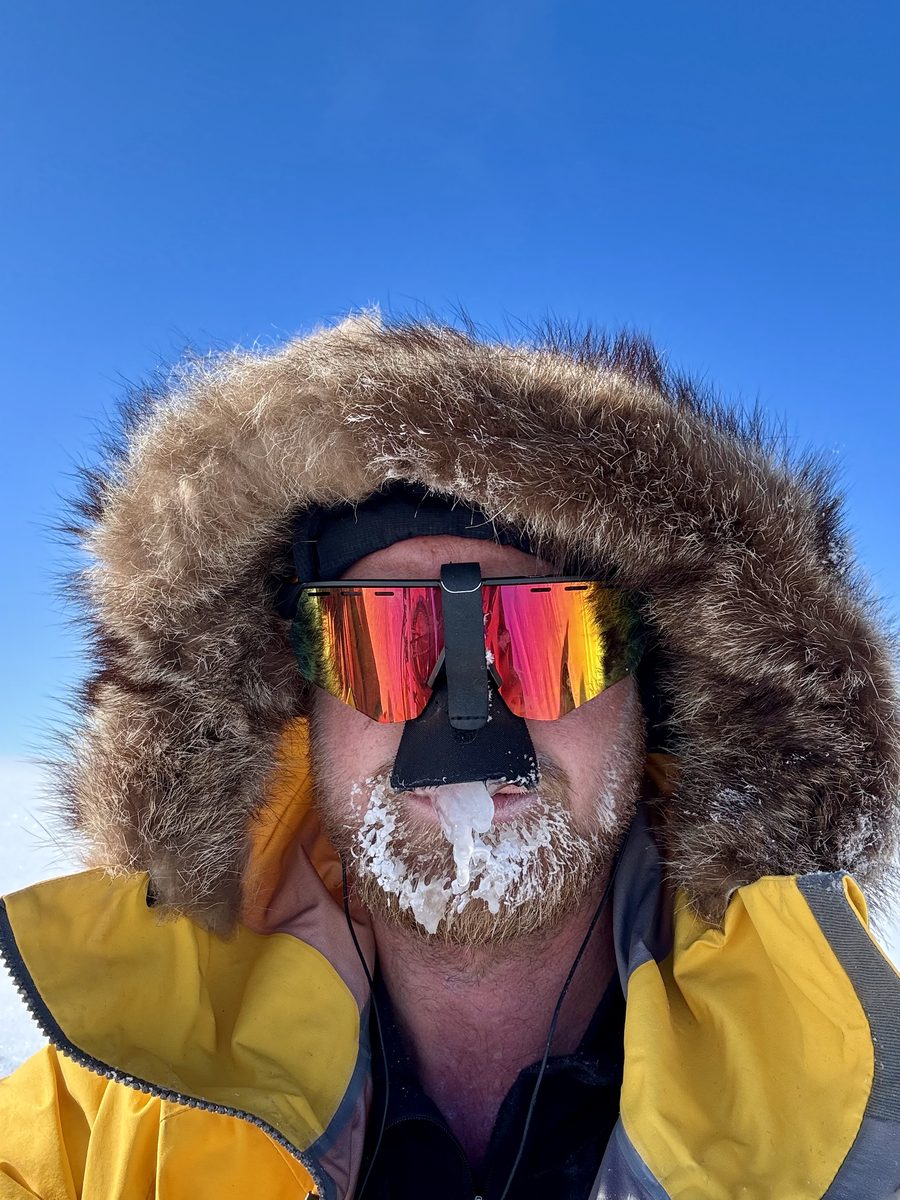 Sam Cox in Arctic conditions, fur-hooded parka against a clear sky